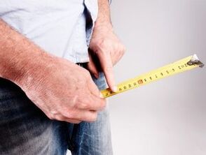 un hombre mide un pene antes del aumento con refresco
